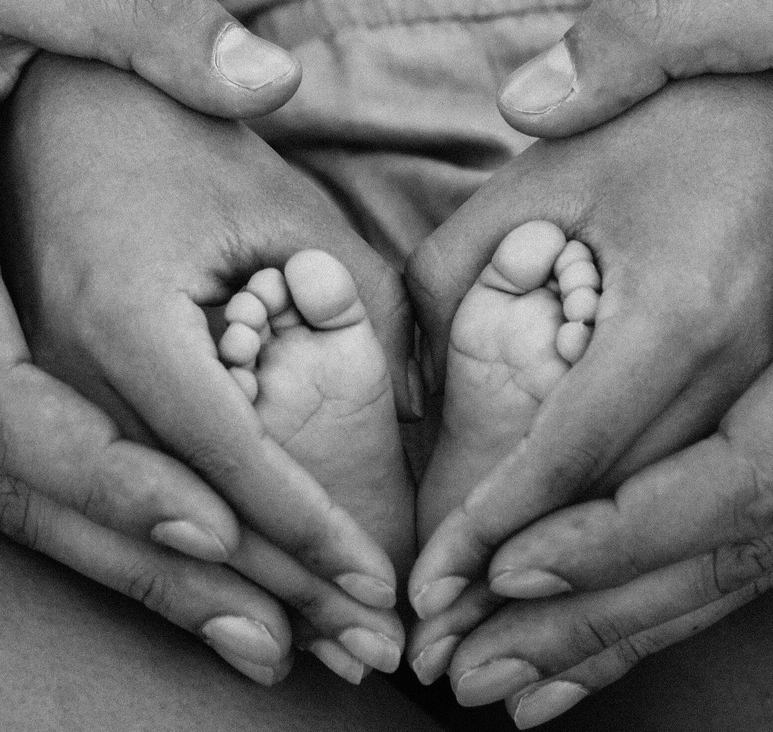 baby feet held together in a heart by two adult hands