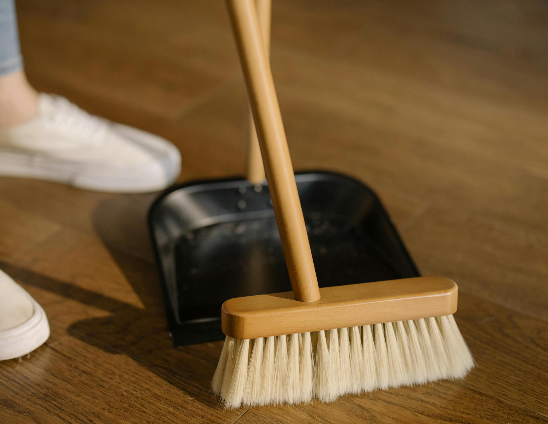 adults feet and a broom and dust pan