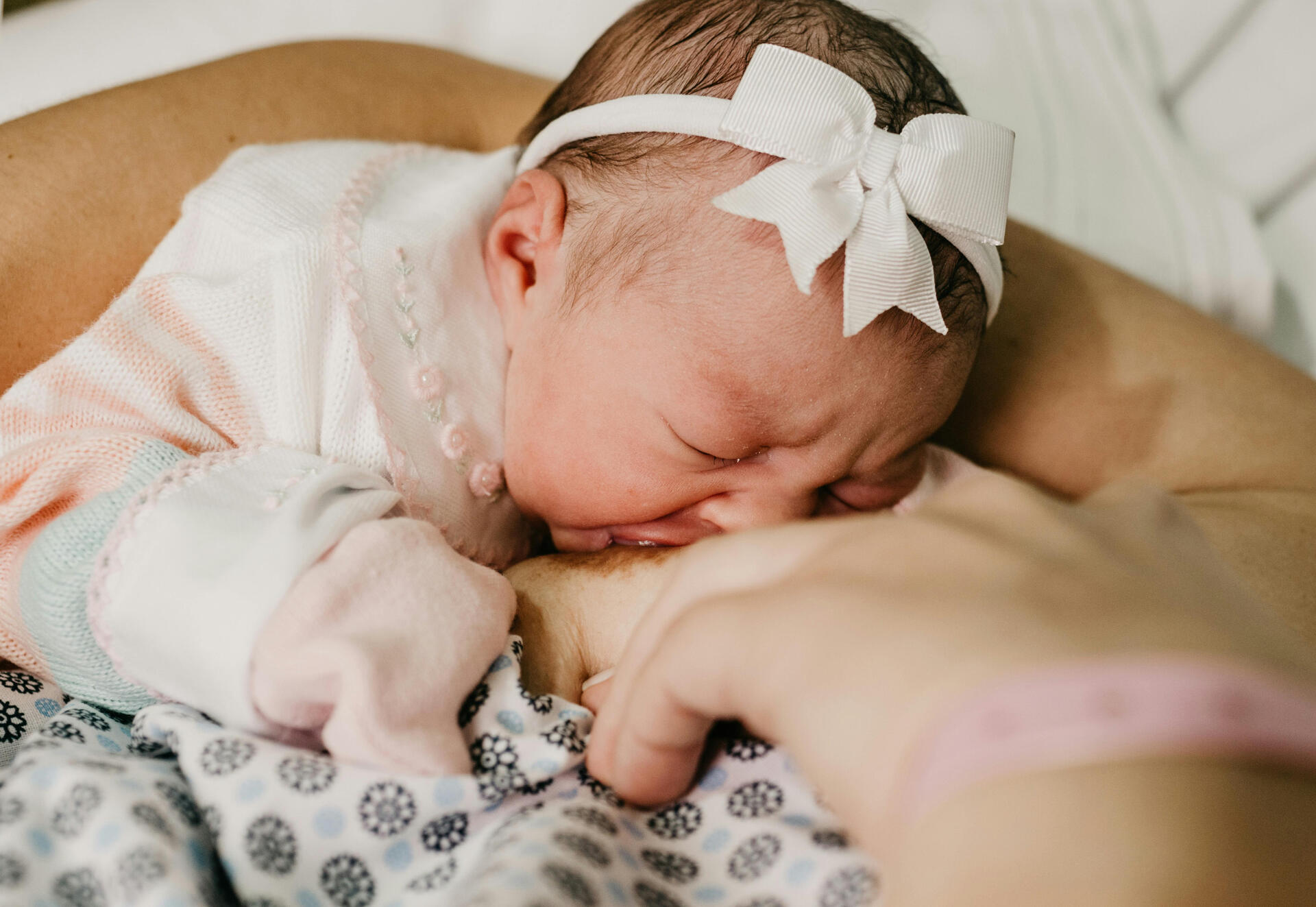 a baby girl is latched on breastfeeding from her mom